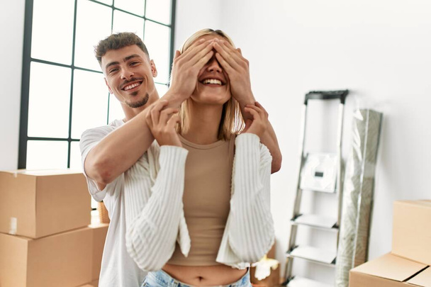 Hombre sorprendiendo a su novia cubriendo los ojos con las manos en el nuevo hogar. - Foto, imagen