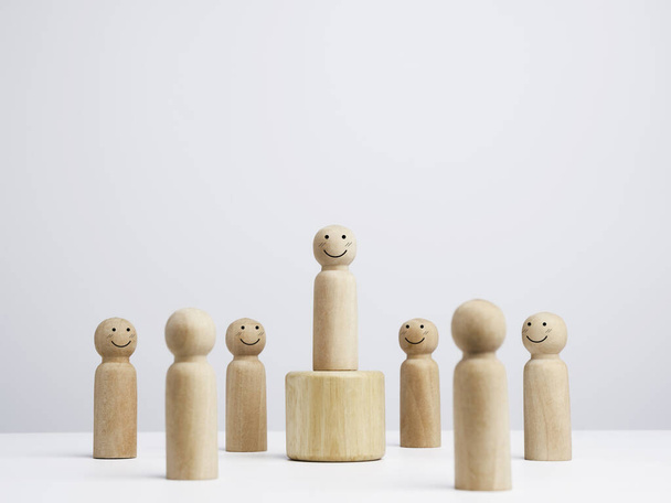 Leader man, influencer, wooden figure, Smiling male standing on the box surrounding with the happy people on white background, minimal style. Leadership, and empowerment, and the winner concept. - Photo, Image