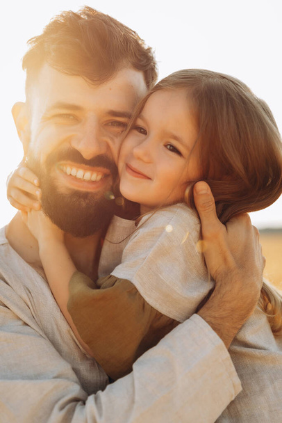 stylish bearded father with his little daughter in his arms  on a walk in the summer park hugging and kissing a baby - Photo, Image