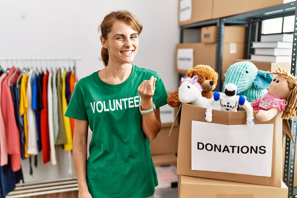 Beautiful caucasian woman wearing volunteer t shirt at donations stand doing money gesture with hands, asking for salary payment, millionaire business  - Photo, Image