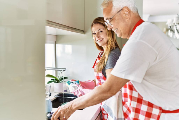 Middle age hispanic couple smiling happy washing dishes at the kitchen. - Foto, imagen