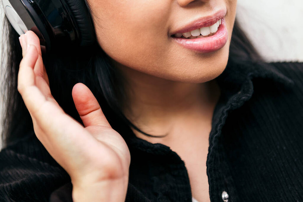 close up of the smile of a cheerful young woman with headphones enjoying listening to music - Fotó, kép