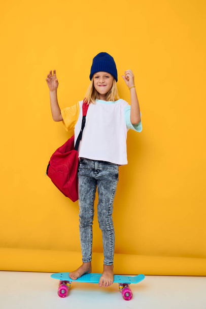 schoolgirl with a skateboard on his head yellow background - 写真・画像