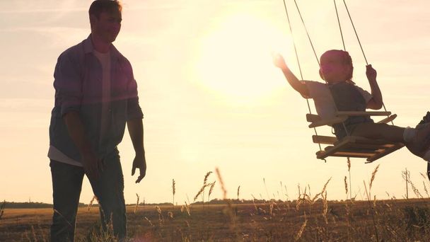Criança feliz com um ursinho de pelúcia e pai está montando um balanço ao pôr do sol no parque, jogando o avião voando no ar. Filha e pai estão se divertindo ao amanhecer. Conceito de vida familiar feliz. Miúdo - Foto, Imagem
