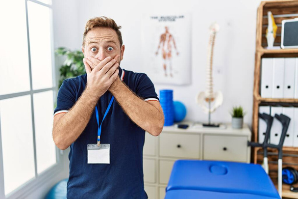 Fyzioterapeut středního věku, pracující na klinice pro zotavení bolesti, šokoval, když si zakryl ústa rukama, aby se nespletl. tajný koncept.  - Fotografie, Obrázek