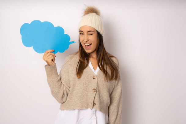 Young smiling woman in winter clothing holding paper cloud isolated over white background. - Photo, Image