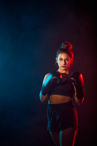kobieta uprawiająca boks lub kickboxing z kolorowymi światłami i dymem. Kopiuj miejsce na reklamę. - Zdjęcie, obraz