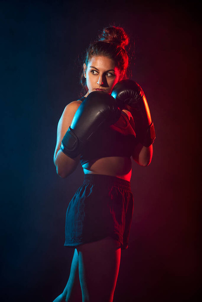 Mladá žena dělá boxerský trénink, nosí boxerské rukavice. - Fotografie, Obrázek