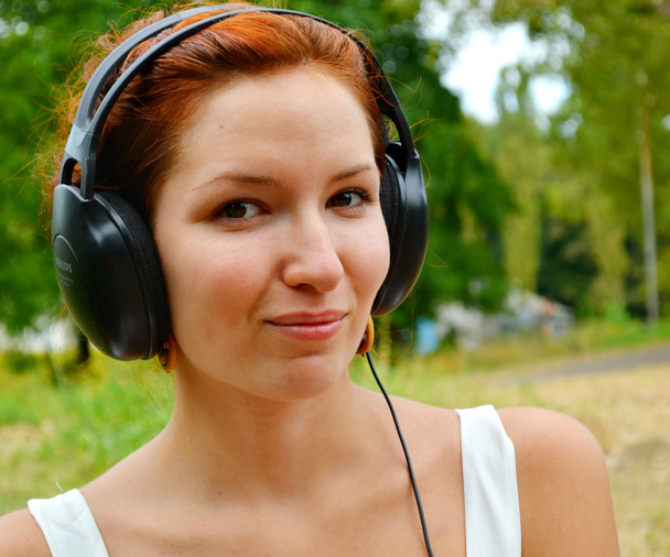 幸せな笑顔で音楽を聴く大きなヘッドホンで美しい赤毛の女性 - 写真・画像