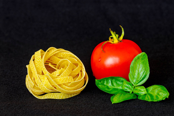 Tomaattipasta ja basilika mustalla taustalla - Valokuva, kuva