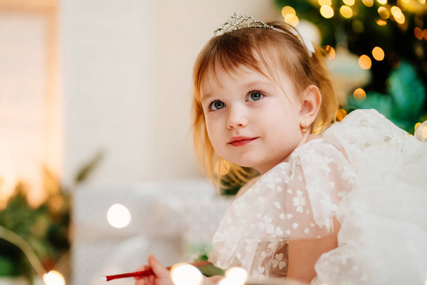 little girl writes a letter to Santa Claus under the Christmas tree. - Foto, Imagem