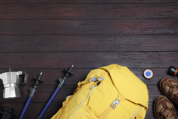 Flat lay composition with tourist backpack and other camping equipment on wooden background, space for text - Photo, Image
