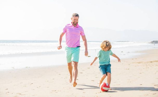 Çocuklar ve babaları yaz tatilinde plajda top ve mutlulukla koşuyorlar. - Fotoğraf, Görsel