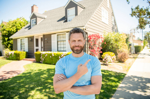 boldog szakállas férfi ujjal mutogat az új ház, ingatlanügynök - Fotó, kép