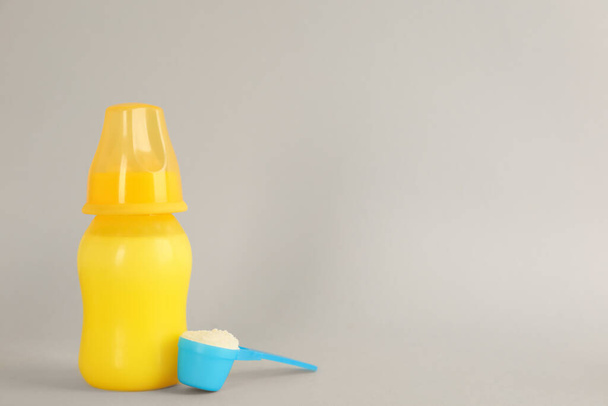 Feeding bottle with infant formula and scoop of powder on light grey background, space for text. Baby milk - Fotoğraf, Görsel
