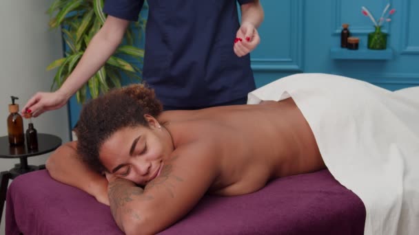 Massagista derramando óleo de massagem para os braços, massageando a mulher de volta dentro de casa - Filmagem, Vídeo