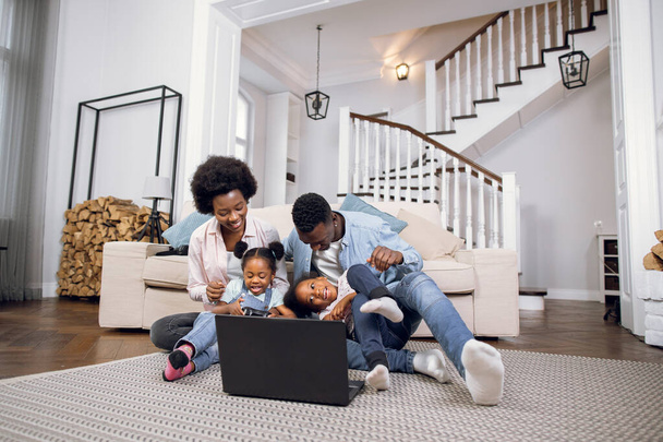 African american family sitting on floor and using laptop - Foto, immagini