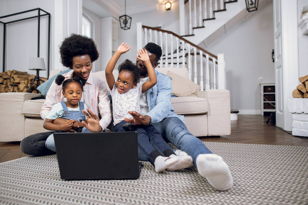 African parents with daughters playing games on laptop at home - Valokuva, kuva