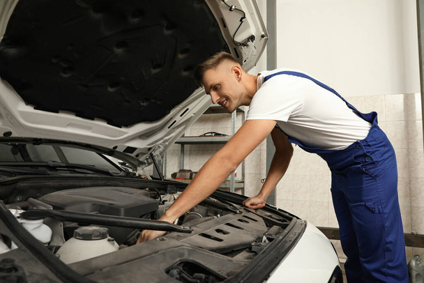Professional mechanic checking modern car at automobile repair shop - Foto, afbeelding