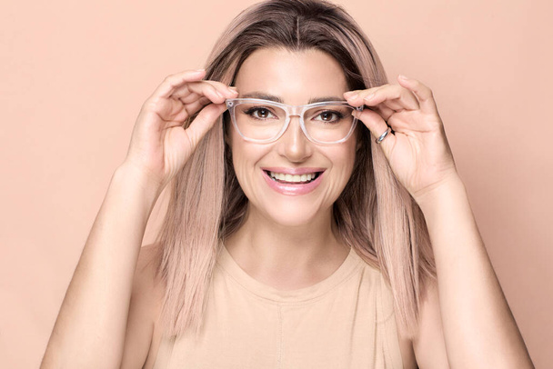 Happy smiling beautiful woman adjusting her eyeglasses with transparent frames Eye wear, and vision care concept - Photo, Image