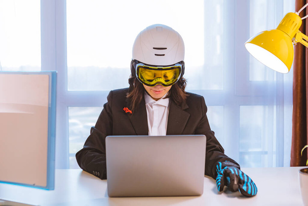 kobieta w sprzęcie narciarskim pracująca na laptopie w biurze marząca o zimowych wakacjach - Zdjęcie, obraz