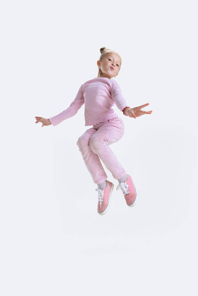 Happy little active Caucasian preschool girl jumping, having fun isolated over white background - Fotografie, Obrázek