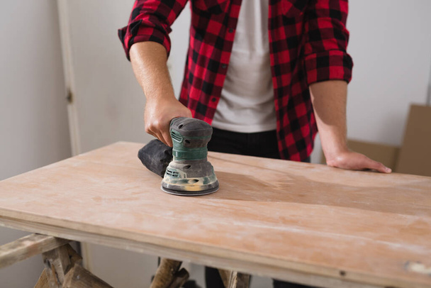 close up of man working with electric sander - Photo, image