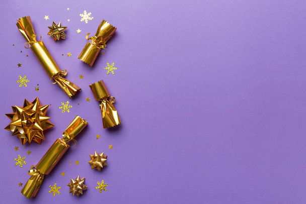 Kerst crackers met glanzende confetti op kleur achtergrond, bovenaanzicht, kopieer ruimte. - Foto, afbeelding