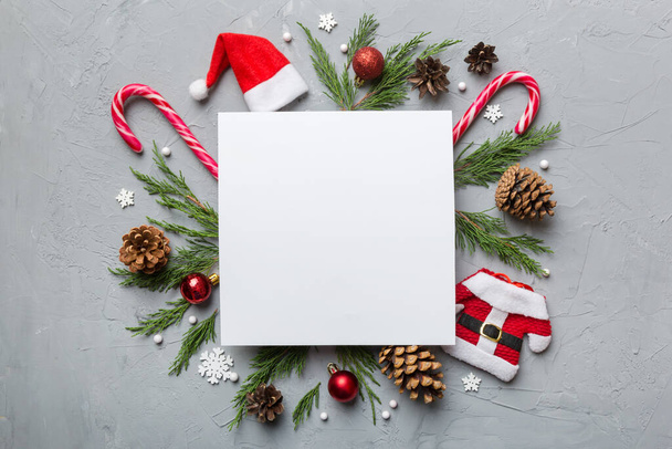 Flat lay Christmas composition. square Paper blank, pine tree branches, christmas decorations on Colored background. Top view, copy space for text. - Valokuva, kuva