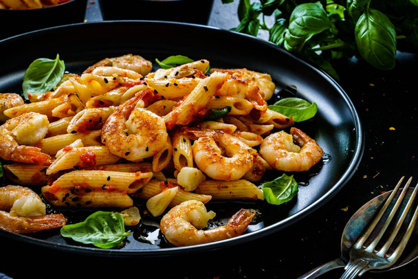 Penne with fried prawns in on black wooden background  - Photo, Image