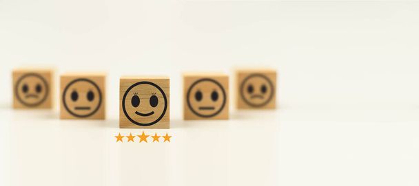 笑顔の顔を持つこのフィードバック木製キューブ幸せな笑顔の顔のアイコンは、サービスに満足を与えるために。とても感銘を受けました。黒、顧客サービスと満足コンセプト。コピースペース,選択フォーカス. - 写真・画像