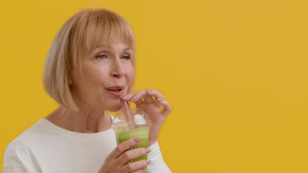 Boldog gyönyörű Senior nő ivás zöld Smoothie Koktél szalma - Felvétel, videó
