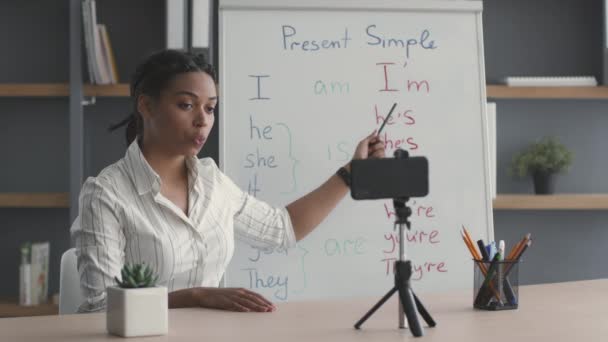 E-öğrenme konsepti. Genç Afro-Amerikan bayan öğretmen İngilizce dersi kaydediyor, akıllı telefon kamerasıyla konuşuyor. - Video, Çekim