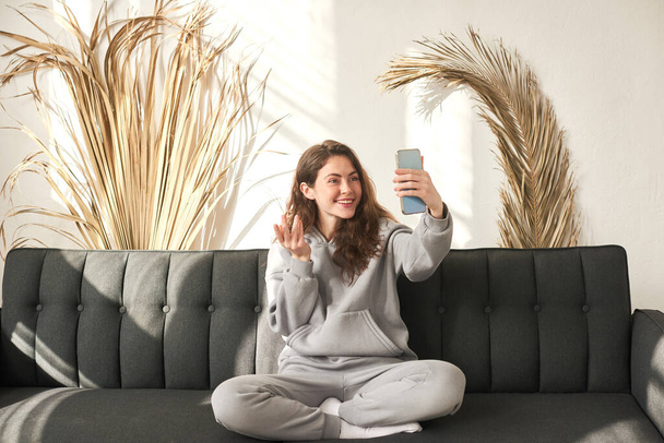 Счастливая женщина совершает видеозвонки со смартфоном на дому, используя приложение для онлайн-встреч с зумом, социальную дистанцию, работу из дома - Фото, изображение