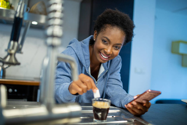 Portrait young black woman with coffee holding mobile phone  - Foto, Imagen