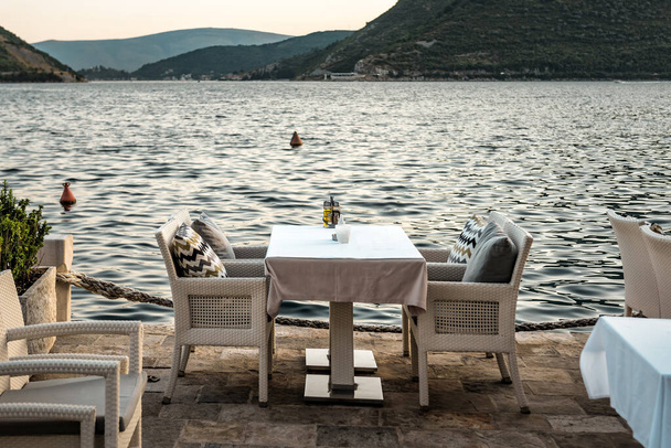 Пляжный ресторан с видом на море. Стол накрывают два человека - Фото, изображение
