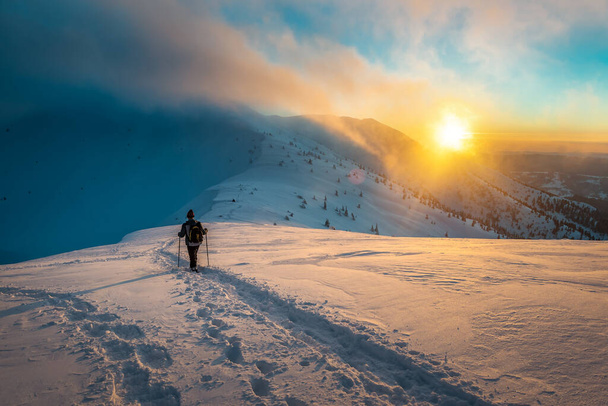 wandelen toerist bij zonsondergang in besneeuwde winterbergen - Foto, afbeelding