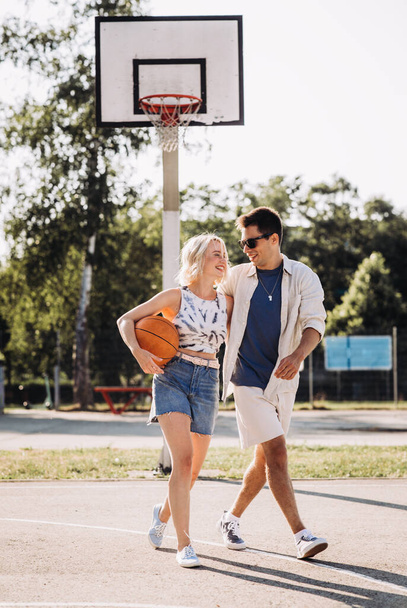 happy couple with ball on basketball playground - Foto, afbeelding