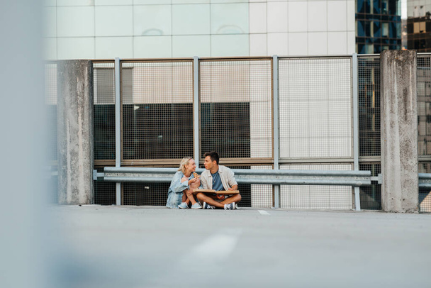 happy couple eating pizza on city roof top parking - Fotoğraf, Görsel