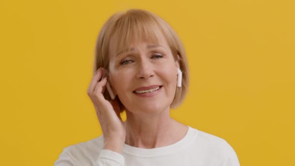 Usmívající se starší žena poslech hudby v bezdrátových Airpody sluchátka, těší oblíbená píseň - Záběry, video