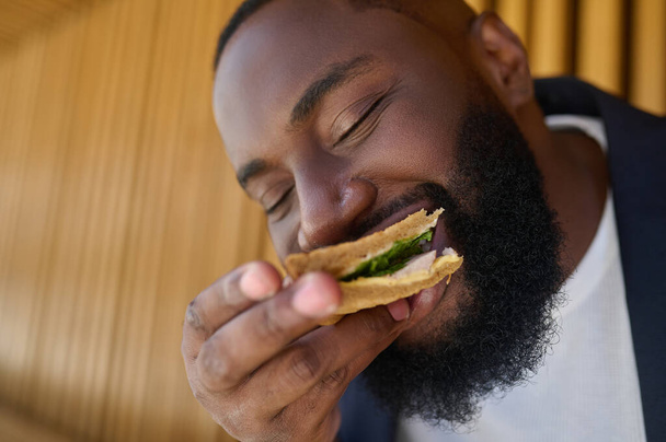 A dark-skinned maneating snadwich with a big appetite - Foto, Imagen