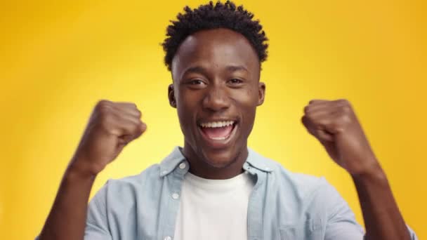 jong afrikaans amerikaans guy juichend gelukkig, schudden vuisten en lachen naar camera, ondersteuning over gele achtergrond - Video