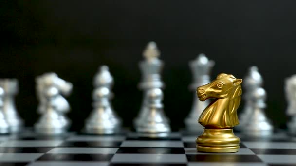 Złoty koń szachowy pukać i zdobyć srebrny zespół na czarnym tle (Koncepcja strategii firmy, zwycięstwo biznesowe lub decyzja) - Materiał filmowy, wideo