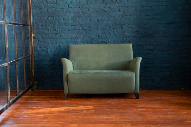 zöld puha kanapé közel a kék fal a fa padló a szobában, kárpitozott bútorok a lakásban, kanapé a hallban, minimalizmus - Fotó, kép