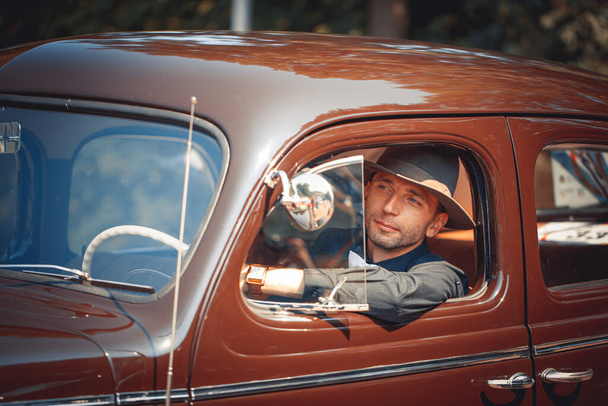 Jongeman zittend in retro auto - Foto, afbeelding