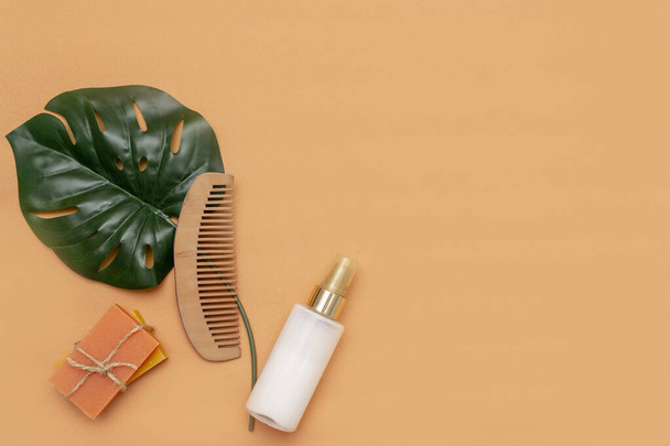 Bathroom accessories with zero solid soap waste, cosmetic sprayer, wooden comb with a monstera leaf on a beige background. - Foto, Imagem