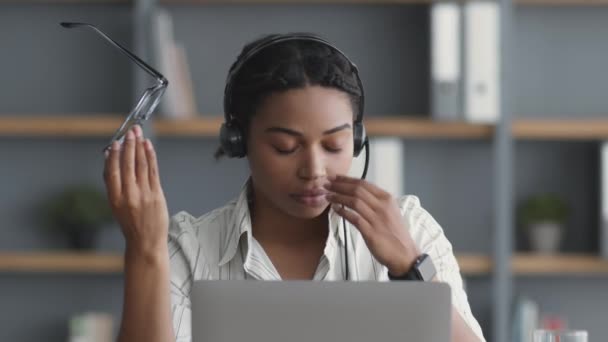 Koncept přepracování. Unavená africká americká dáma call centra operátor trpí bolestí hlavy, tření nosu most - Záběry, video