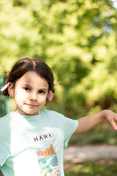 Pequena menina branca bonita com grandes olhos sorridente olha para a câmera no fundo rústico borrado com bokeh. Retrato vertical do país - Foto, Imagem
