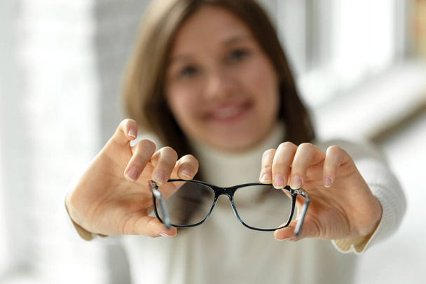 Γυναίκα με κακή όραση. Ένα όμορφο κορίτσι φοράει γυαλιά για να βελτιώσει την όρασή της. - Φωτογραφία, εικόνα