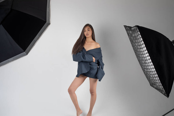 Attractive asian woman in a jacket posing in a photo studio on a white background. - Zdjęcie, obraz